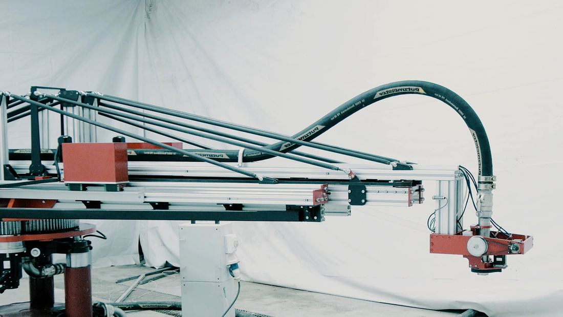 A compact construction 3D printer with a long arm on a building site