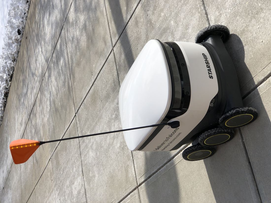 A delivery robot rolling over a snowy path