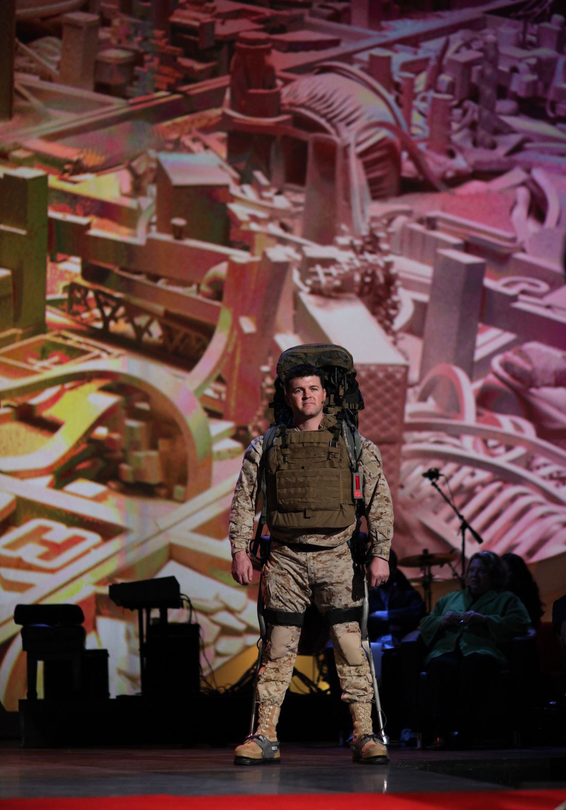 A person walking on stage with a powered leg exoskeleton