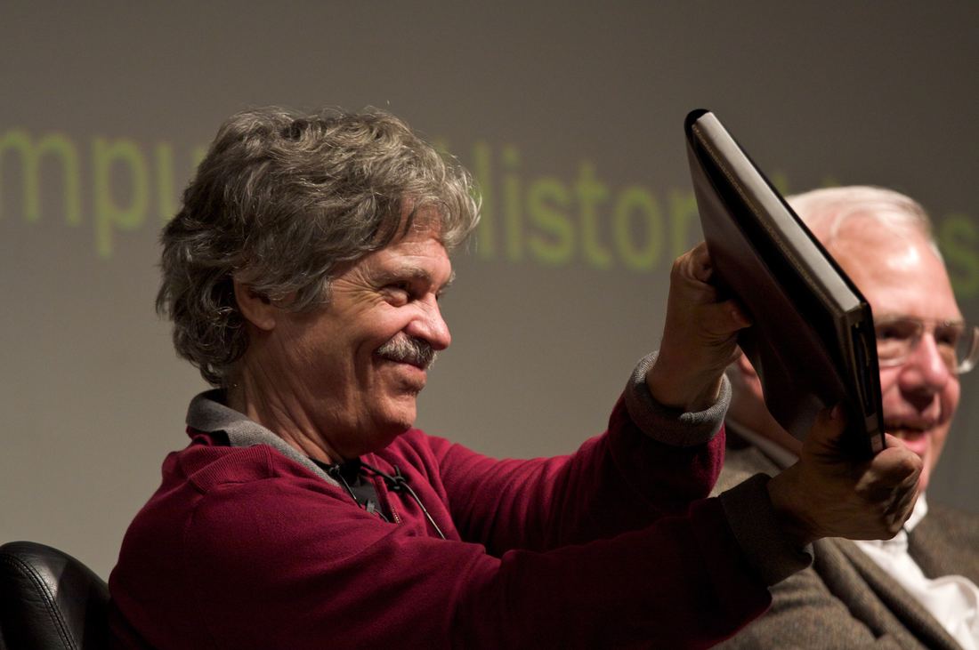 Computer scientist Alan Kay holding a cardboard model of his Dynabook tablet concept